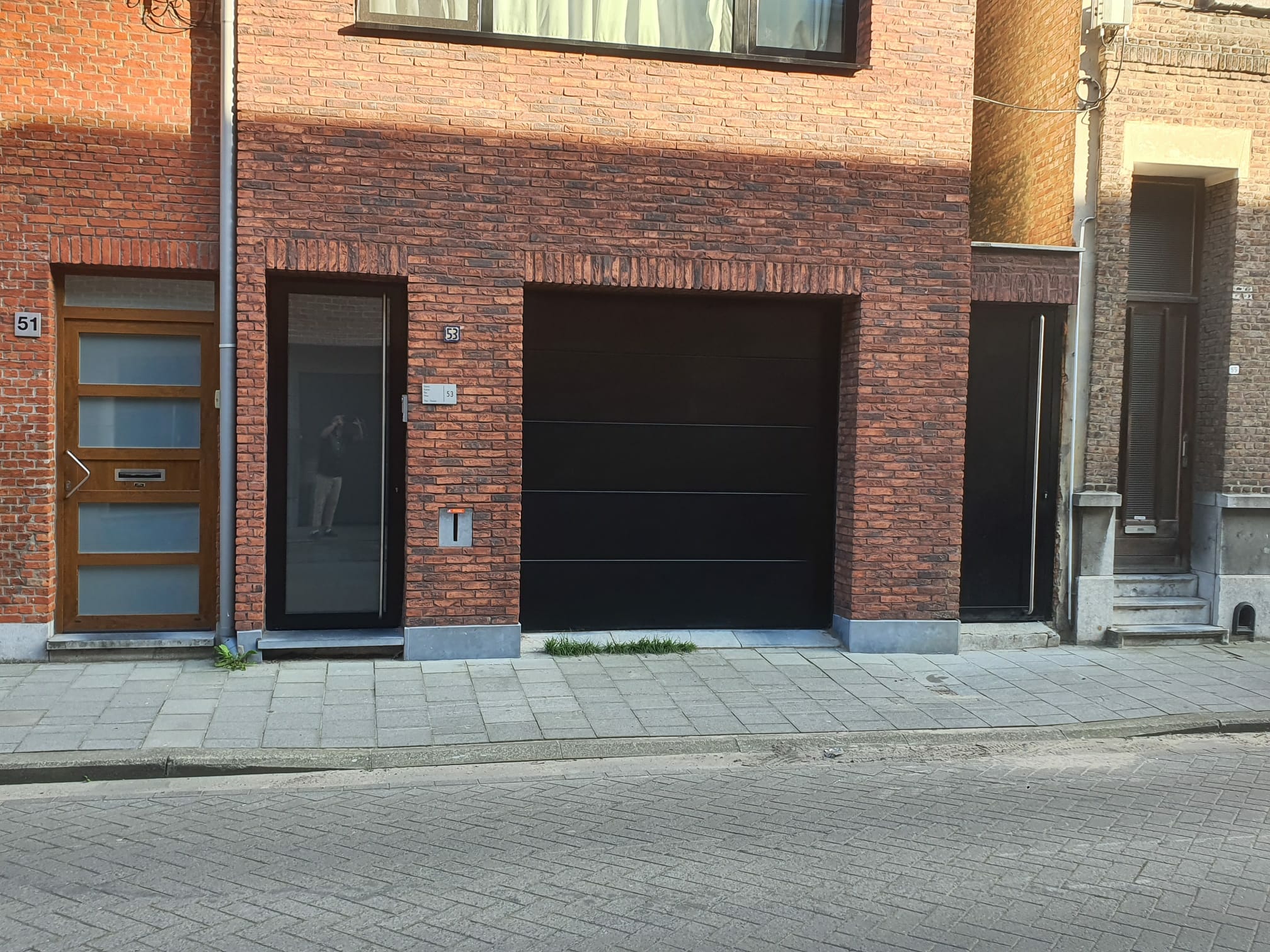 Zwarte deur en garagepoort met zij ingang